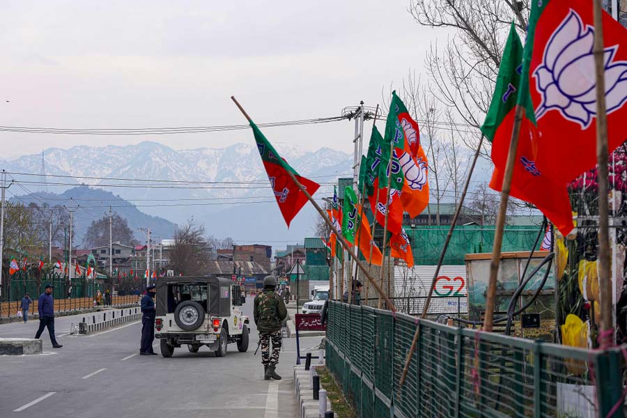 Security personnel stand guard near BJP flags put up along a road ahead of PM Narendra Modi's visit to Kashmir valley, in Srinagar.